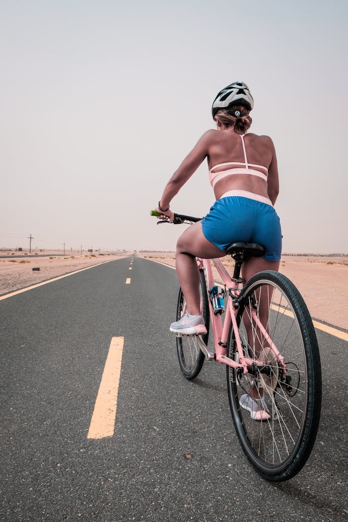 A woman in active wear enjoys cycling along a deserted road in Dubai.