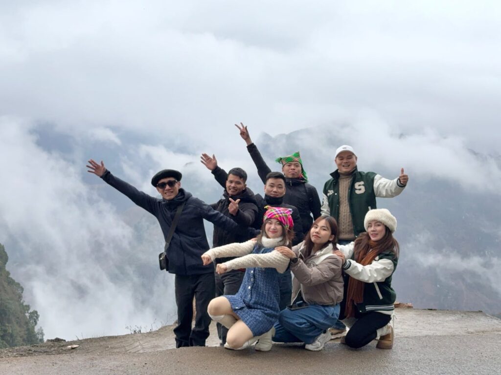 A joyful group of friends posing outdoors on a misty mountain with cloudy background.