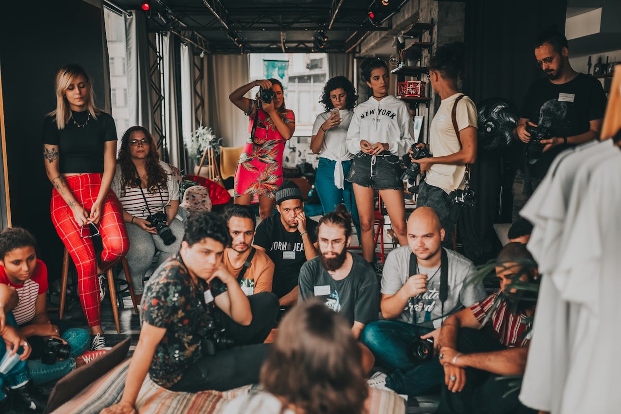 Group of multiracial people wearing casual outfits gathering together in modern studio near female speaker on mat and listening attentively